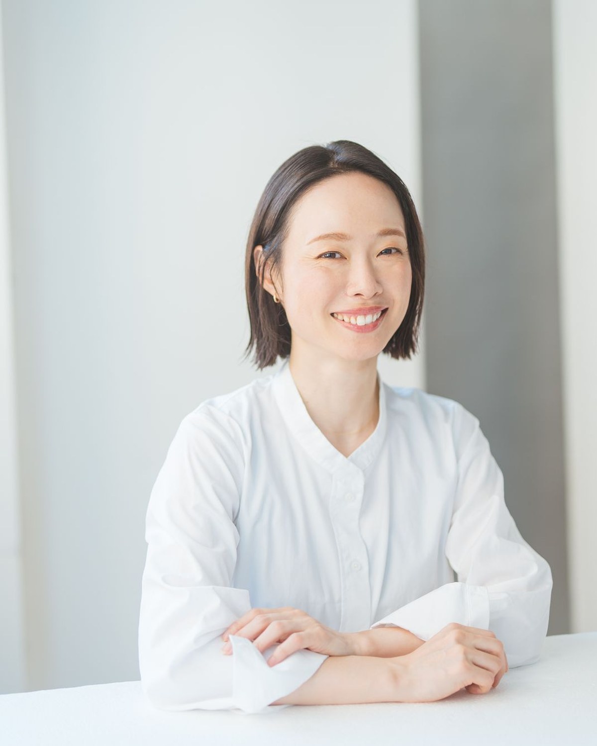 Lin 代表 今井久美子。白いシャツで腕を組み、笑顔でこちらを見ている